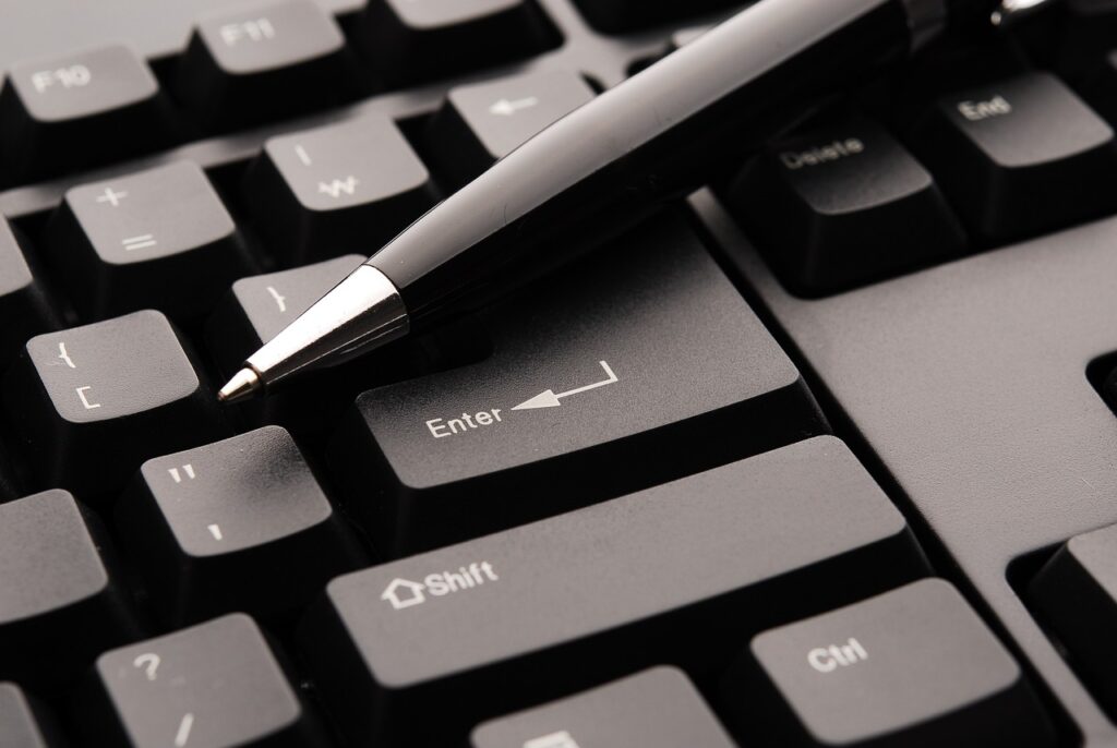black pen resting on a computer keyboard near the Enter and Shift keys